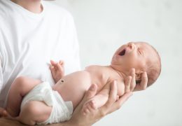 male-hands-holding-a-screaming-newborn-PK5BEHT