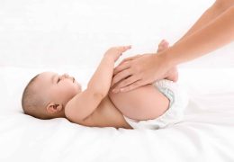 mother-massaging-her-newborn-baby-in-bed-C2AGD3W