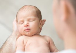 portrait-of-a-newborn-hold-in-father-palms-P73FHDW